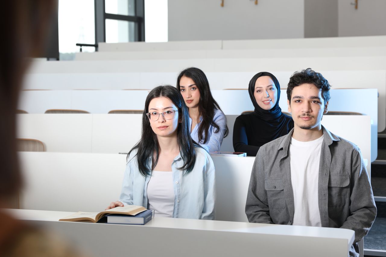 services-03 Group of diverse university students attending a class session in a modern lecture hall.
